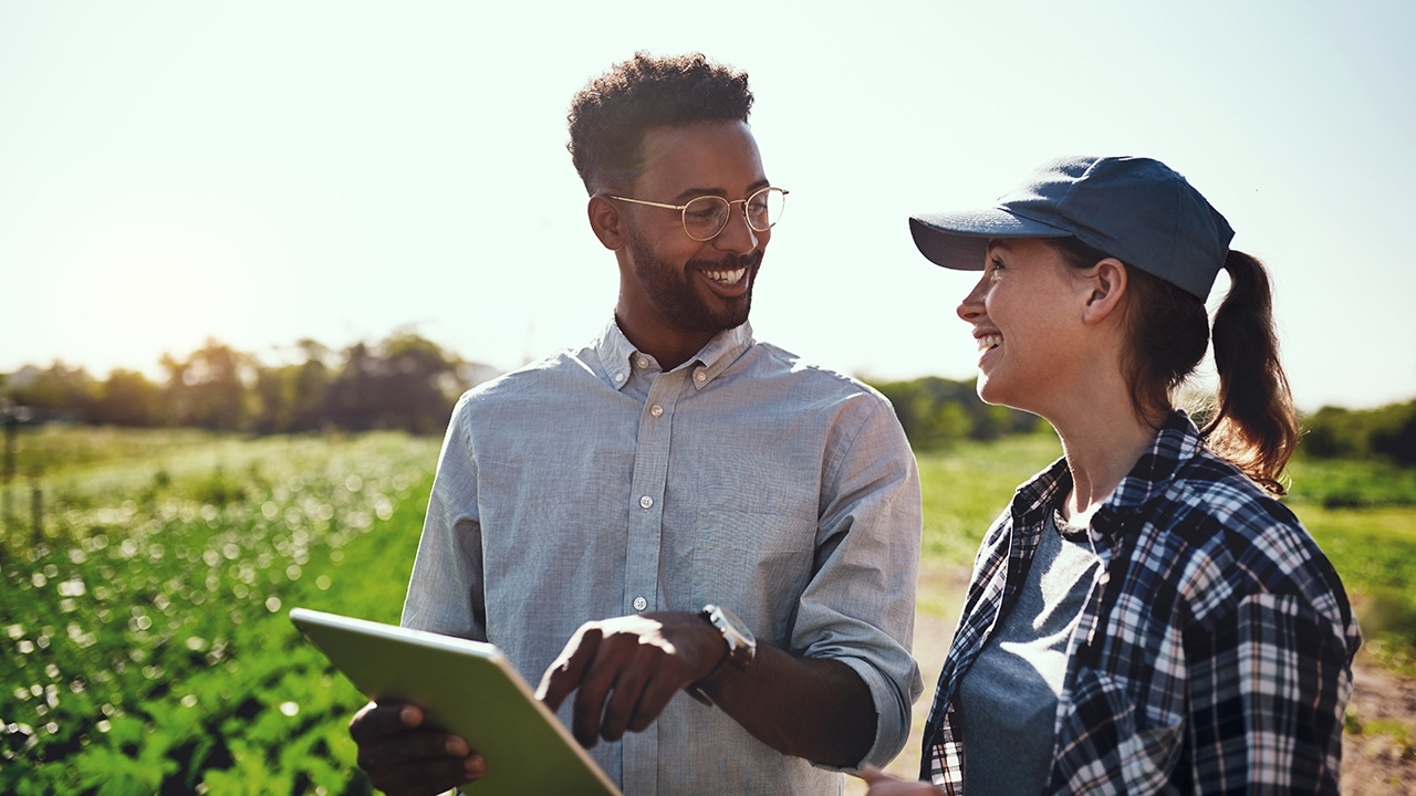 Close-up image of two young farmers looking at a tablet while working on their farm